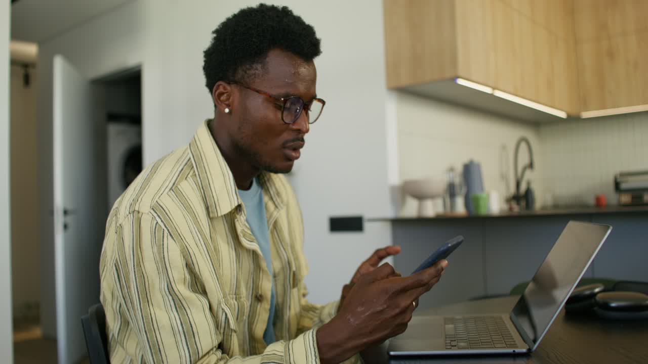 Man using mobile phone and laptop in a kitchen