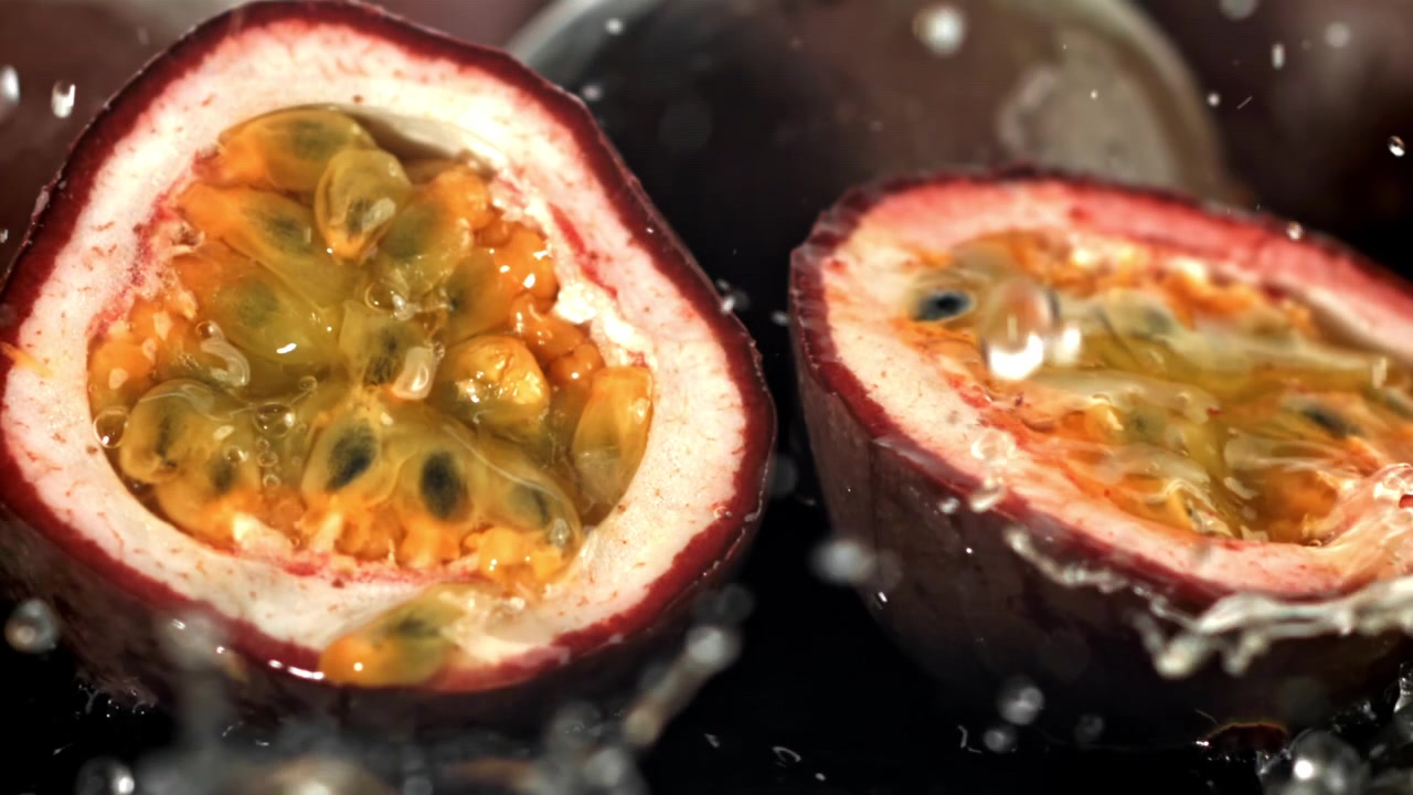 Friske passionsfrugthalvdele med sprøjtende vand i slowmotion