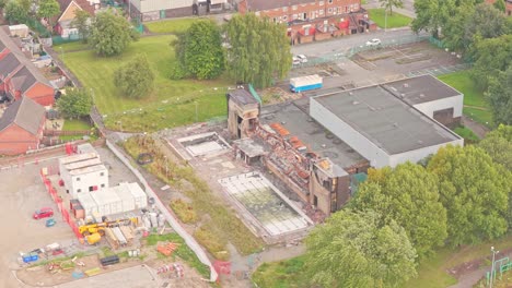 industrial facility with collapsed roof and exposed structure undergoing demolition near residential streets in salford, england, captured in elevated aerial view