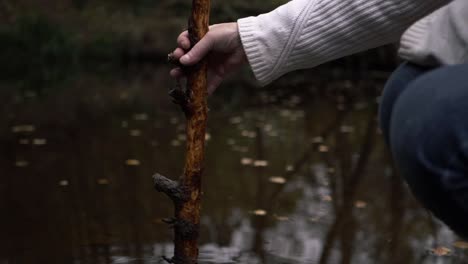 Hand-Entspannt-Sich-Mit-Stock-In-Der-Nähe-Des-Wassers,-Mittlere-Aufnahme