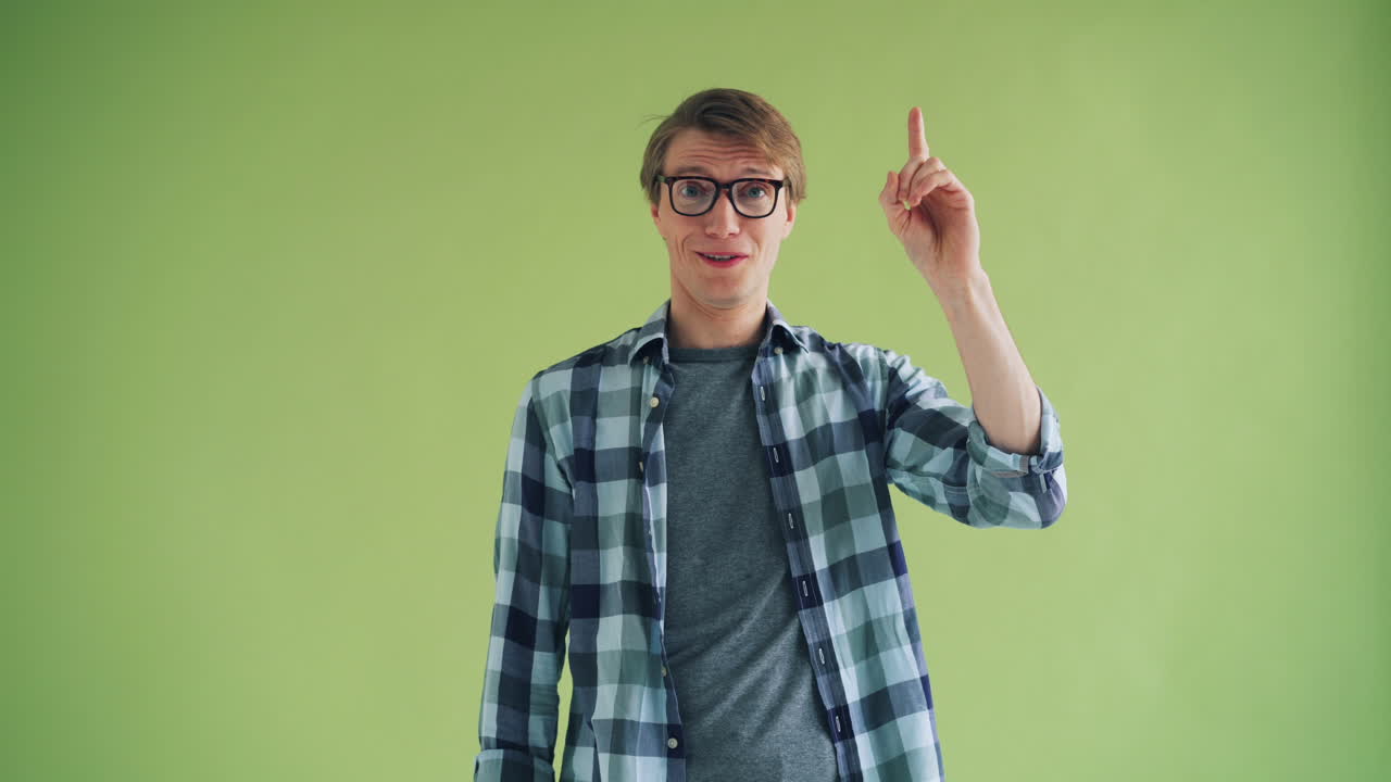 Man with glasses, smiling, and pointing upward