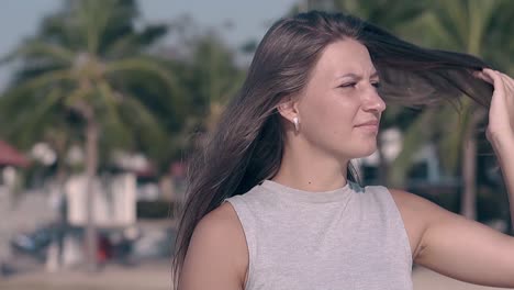 woman with dark hair and earrings poses on beach slow motion