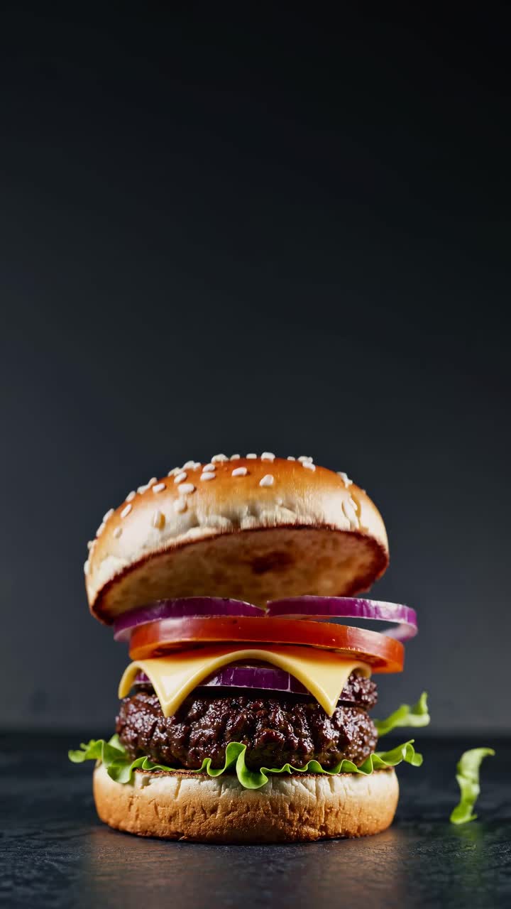 Close-up video of a gourmet burger with lettuce, cheese, tomato, and onion, shot from a low angle