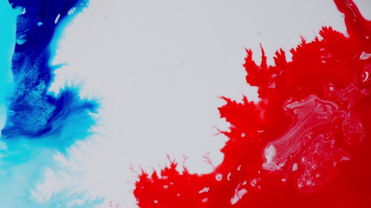 Macro vivace di inchiostro blu e rosso che si mescolano, creando modelli astratti