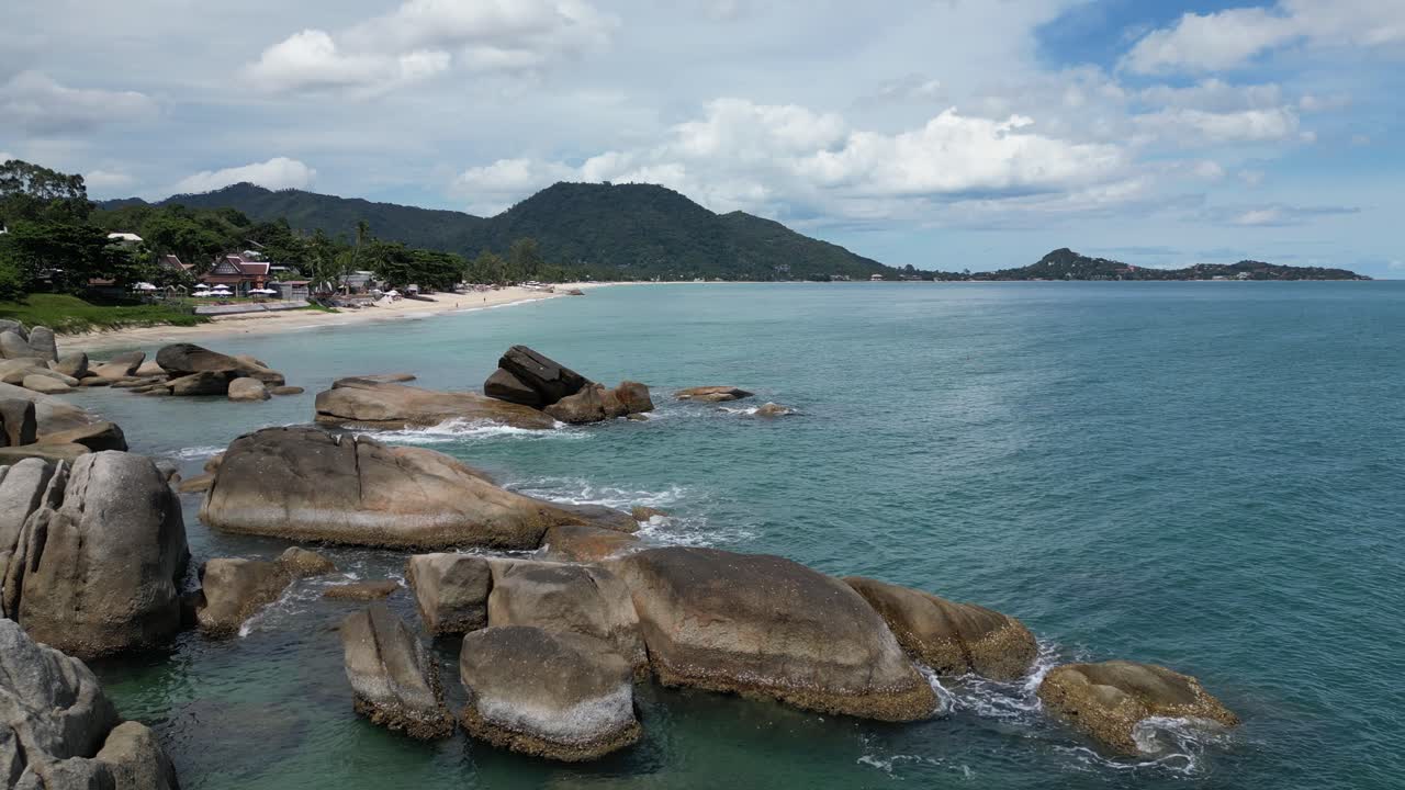 zoom in shot of the rocky coastal area with green mountains and hills visible in the distance