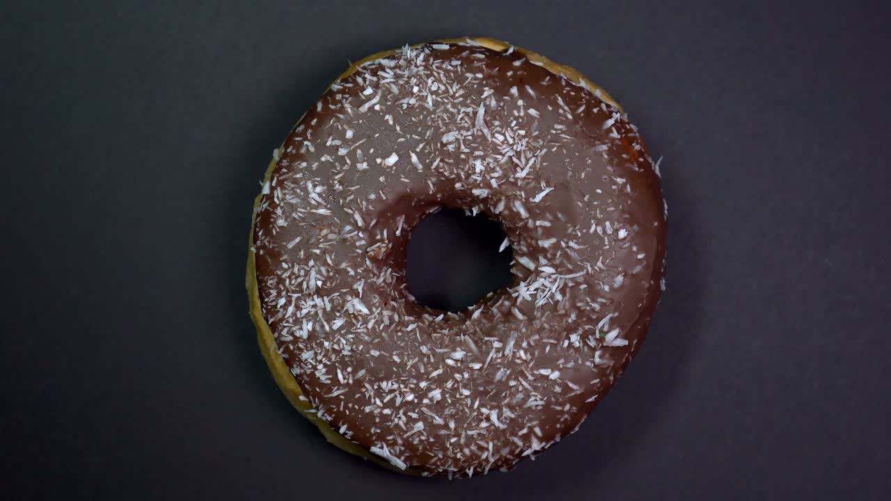 saboroso y fresco rosquilla rosquilla macro disparo de primer plano girando sobre un fondo negro.