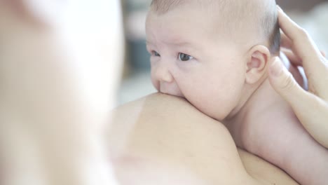 baby doing skin-to-skin with mother in her arms is guided towards the nipple and starts breastfeeding