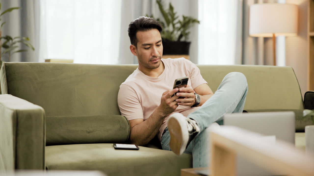 집에서 소파에서 스마트폰을 사용하는 남자