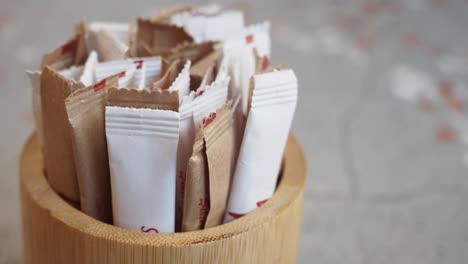 closeup of a wooden sugar dispenser filled with sugar packets