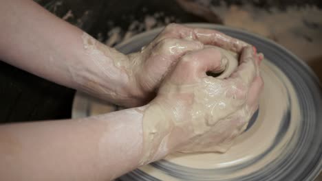 a potter teaches a woman to make clay dishes. a man takes a woman's hands