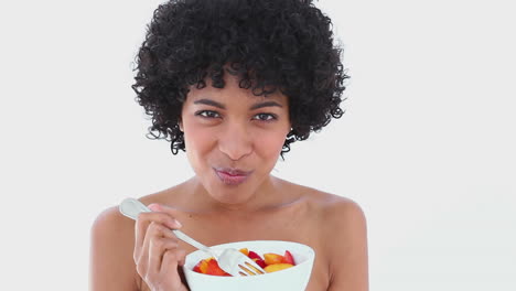 mujer sonriente comiendo una ensalada de frutas