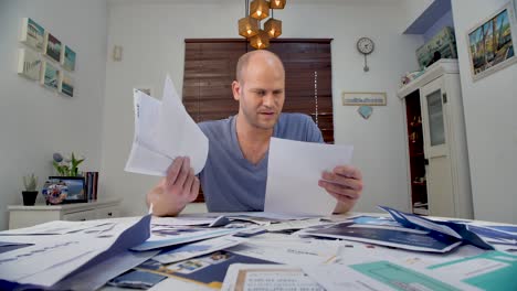 frustrated bald man seating at home and thinking how to pay his bills