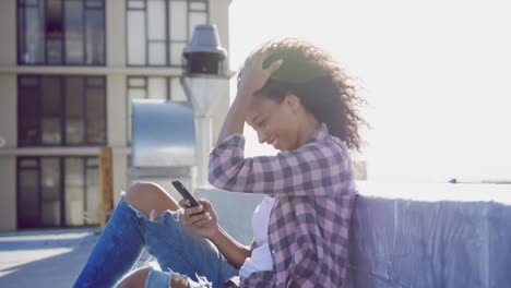 fashionable young woman on urban rooftop using smartphone