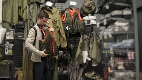 man trying on hunting vest in a store