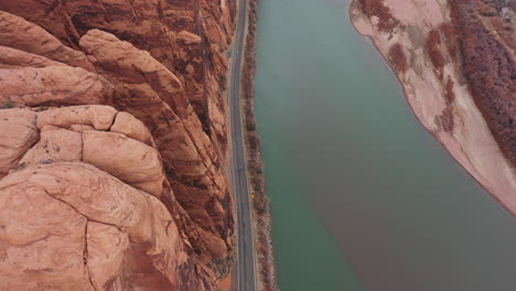 Vista-Aérea-A-Vista-De-Pájaro-De-La-Carretera-De-La-Ruta-Estatal-De-Utah-Por-El-Río-Colorado-Bajo-Escarpados-Acantilados-De-Arenisca