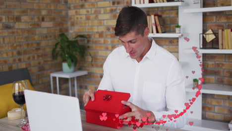 animación de corazones rojos sobre hombre caucásico abriendo caja de regalos roja en una cita de video