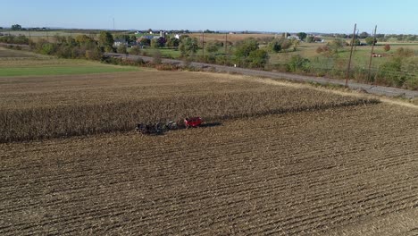 vista aérea de un granjero amish cosechando su cosecha de otoño de maíz con cinco caballos tirando de su cosechadora en un soleado día de otoño