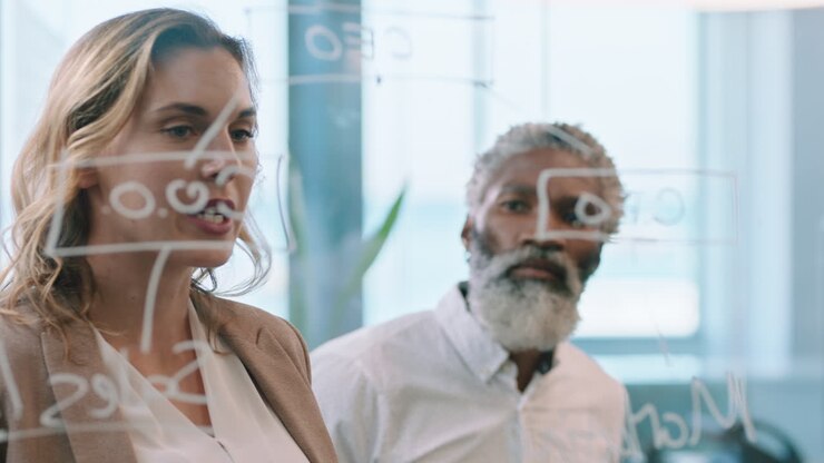business people using sticky notes brainstorming team leader woman working with colleagues writing on glass whiteboard showing problem solving strategy in office meeting