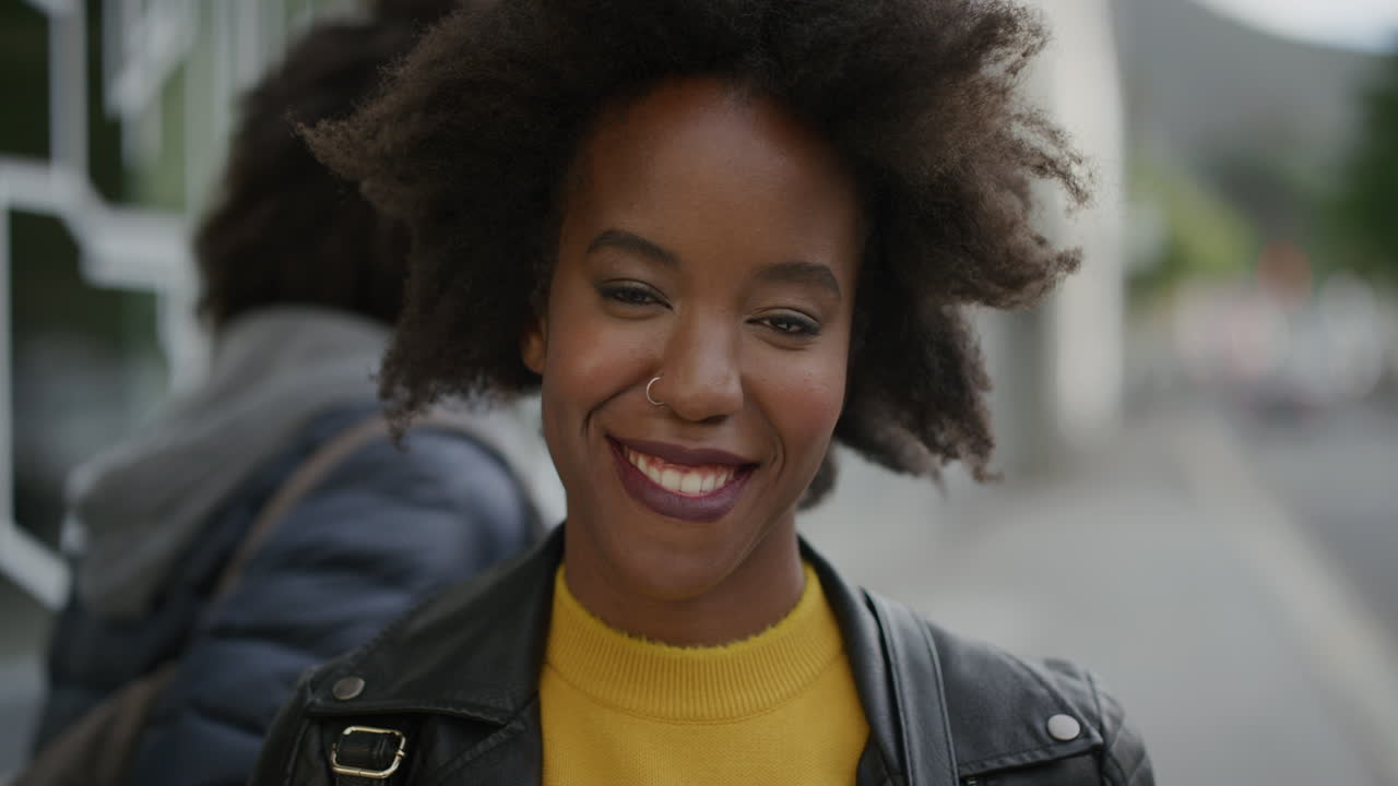 ritratto di elegante donna afroamericana sorridente allegra guardando la telecamera in un contesto urbano vibrante giovane studentessa con funky afro slow motion
