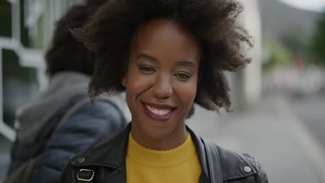 Retrato-De-Una-Elegante-Mujer-Afroamericana-Sonriendo-Alegre-Mirando-La-Cámara-En-Un-Vibrante-Fondo-Urbano-Joven-Estudiante-Con-Funky-Afro-Cámara-Lenta