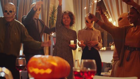 friends dancing with sparklers at halloween home party