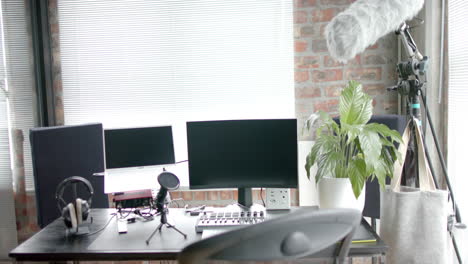 Close-up-of-desk-with-computer,-laptop-and-microphone-at-home,-slow-motion