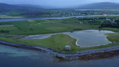 aerial twilight orbit of aughinish island with a martello tower in the foreground and county clare's striking landscape