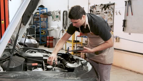 latin adult car mechanic does inspection service on the car engine in a repair shop