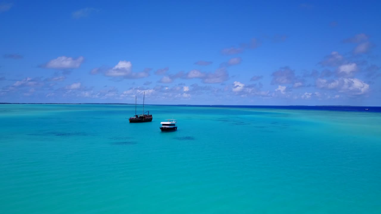 vista aérea de dos barcos turísticos anclados en una isla tropical cubierta de palmeras, acercándose en un día despejado
