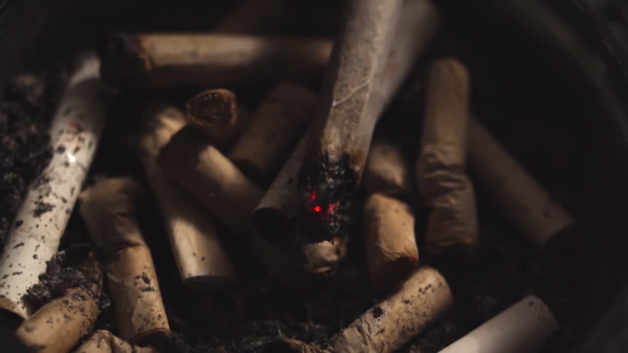 Rolled cigarette extinguishes in the ashtray, close up shot