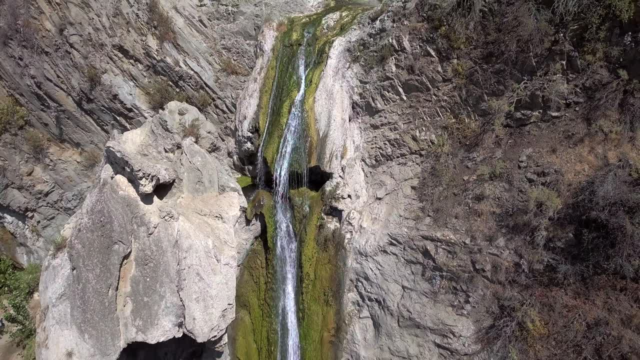 drone aéreo tomando una panorámica, de una cascada mientras vierte agua desde un acantilado