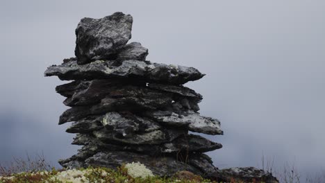 a cairn made of dark jagged stones on a moss-covered rocky terrain