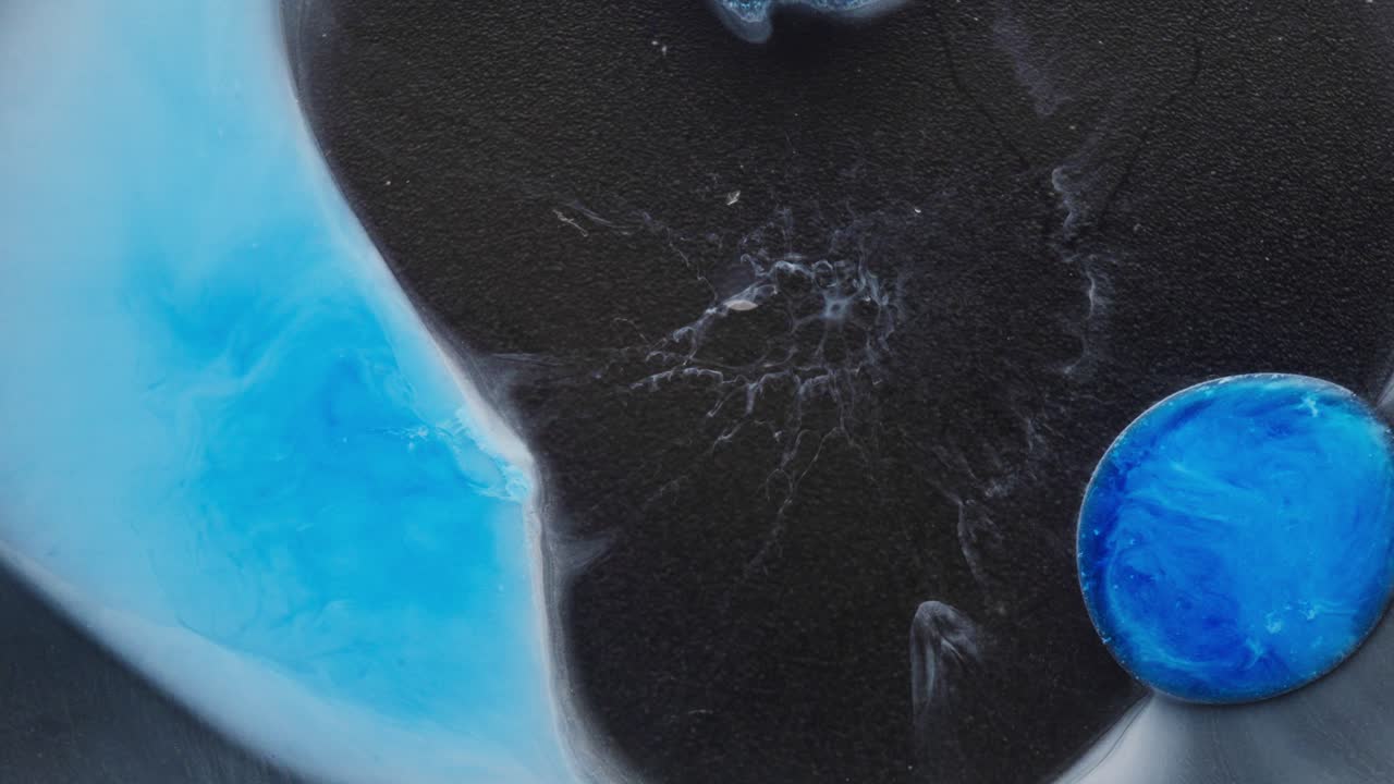 Abstract swirls of black and blue alcoholic ink forming a dramatic macro design