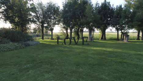 dolly in with drone of a 'love' sign made of plants meant for romantic events during sunset