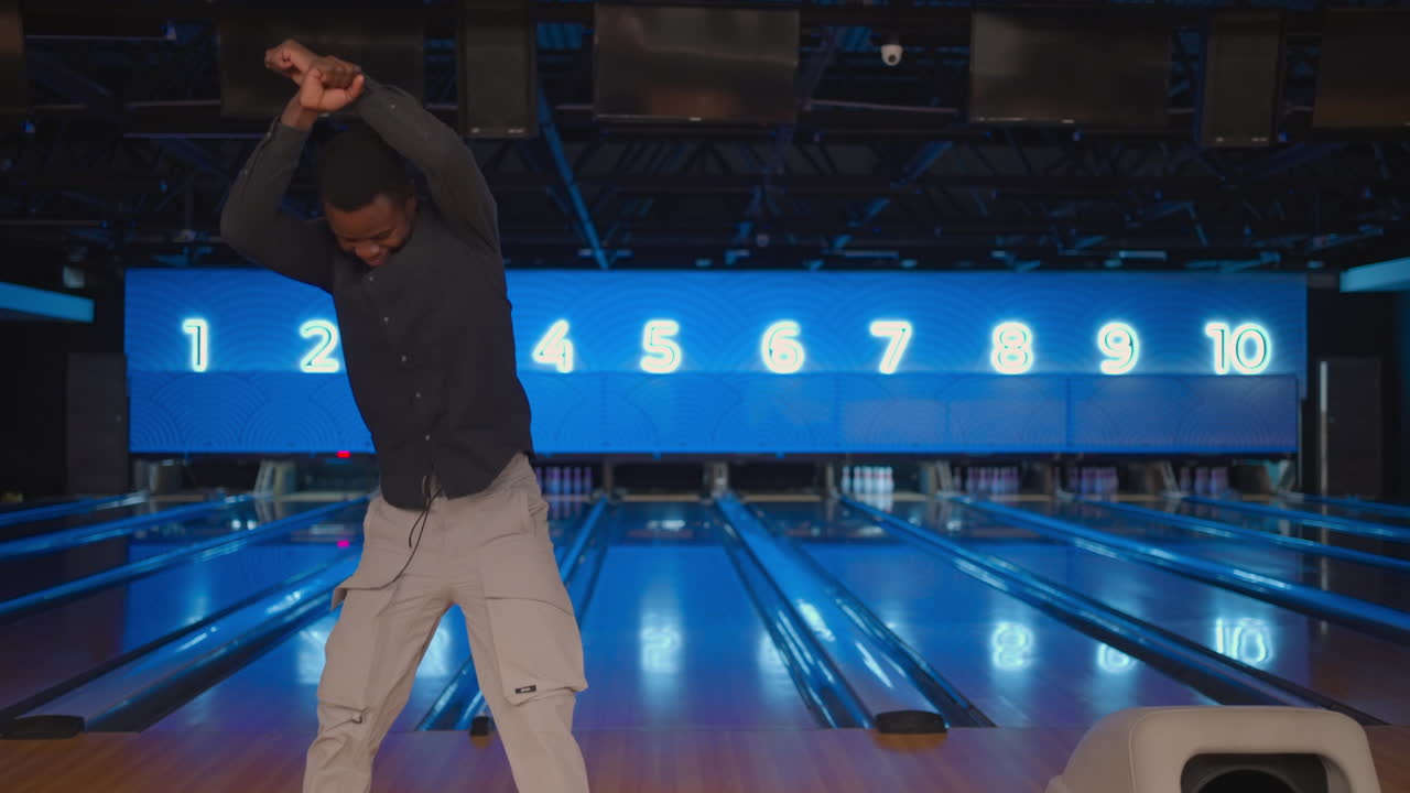 Black man Jump happily looking into the camera celebrate the victory in slow motion. Throw in the bowling alley to make a shoot. Victory dance and jump with happiness.