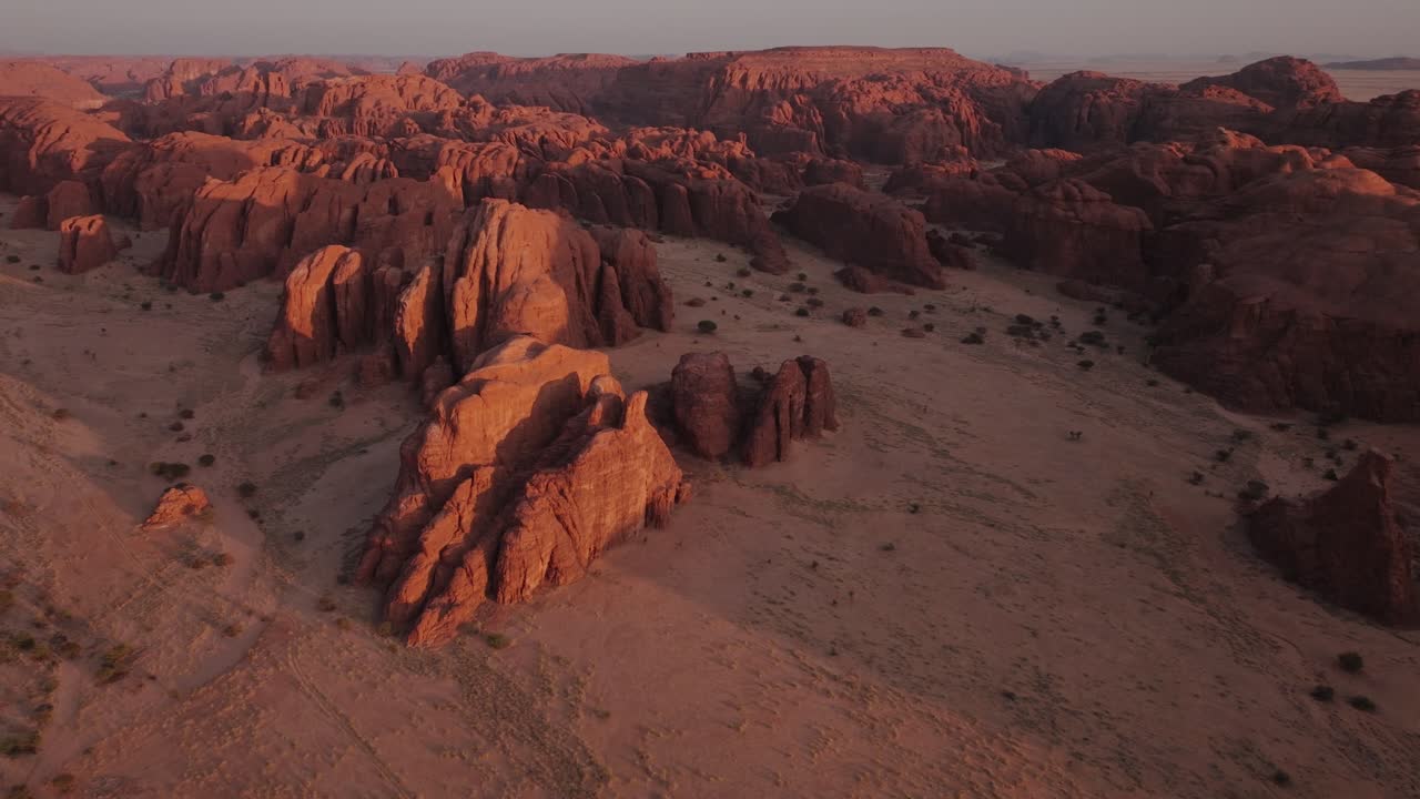 Luftfoto ovenfra med drone af bjerge i sandklitterne i Sahara-ørkenen ved solnedgang.