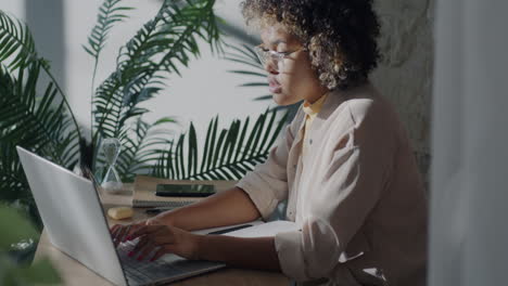 mujer trabajando en una computadora portátil y un cuaderno