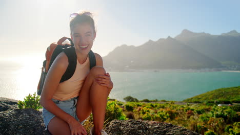 Portrait-Of-Woman-With-Backpack-On-Vacation-Taking-A-Break-On-Hike-By-Sea-On-Coastal-Path