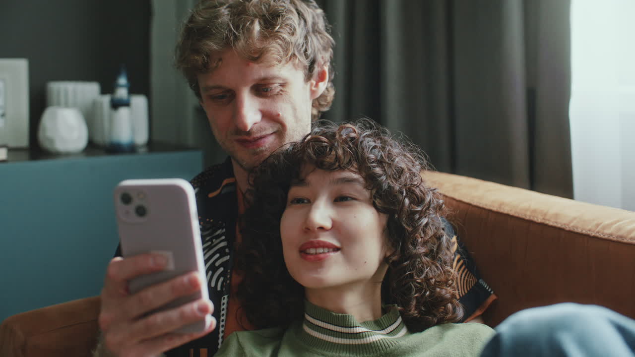 Coppia romantica che guarda un feed di social media sul telefono a casa.
