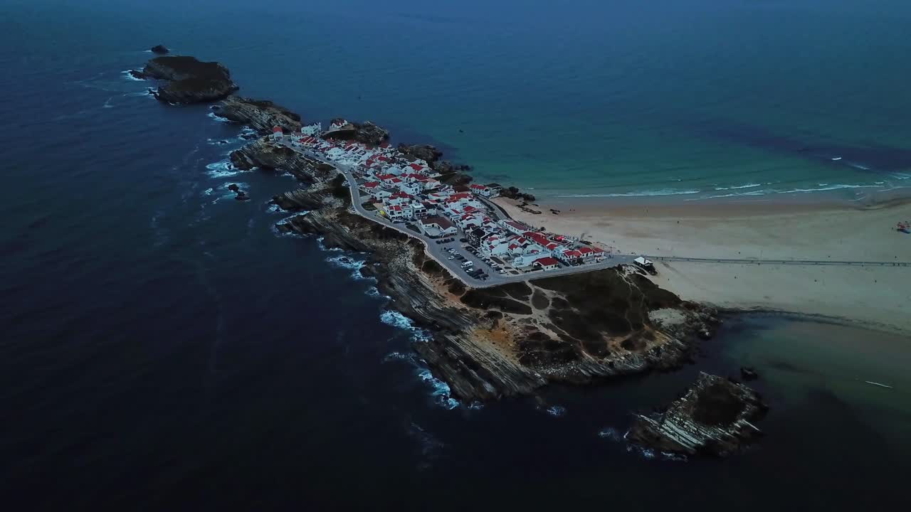Aerial view capturing Baleal island in Peniche, Portugal, during the enchanting blue hour, highlighting the charming town, pristine beach, vast ocean, and rugged coastline.