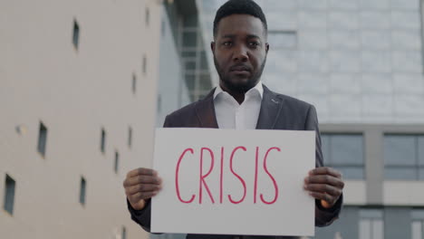 man holding a sign saying crisis