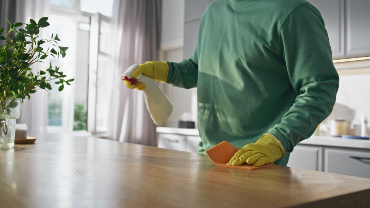 Cleaning service guy shrugging at house closeup. Happy man polishing kitchen