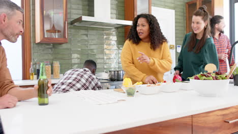 happy diverse male and female friends preparing food together in kitchen