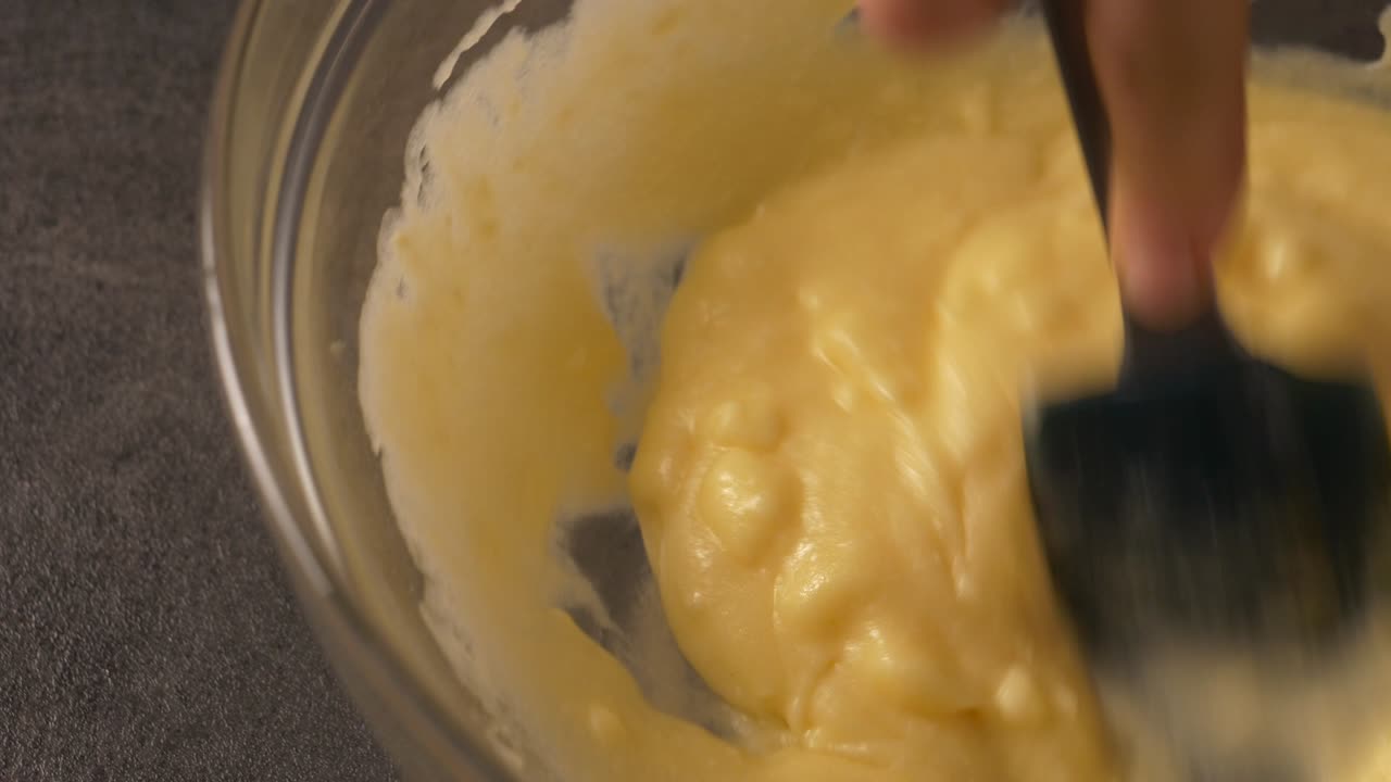 Mixing honey and butter filling for a cake. Close up view of a hand whisking cake batter in home kitchen.