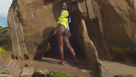 sexy girl shows off her huge assets while standing at the entrance to cave in a thong bikini