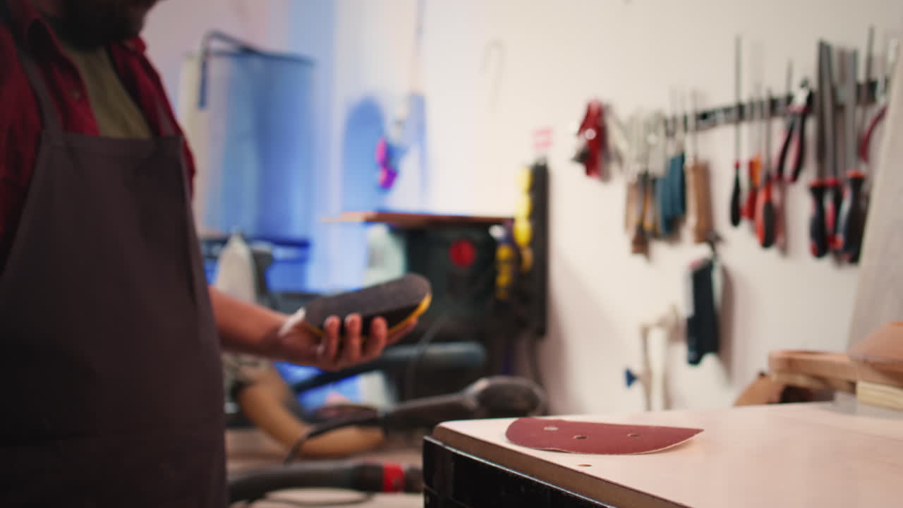 Carpenter putting sandpaper on piece of plastic, creating abrasive sponge