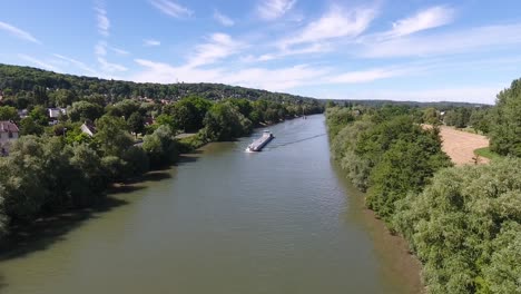 drone disparado volando hacia una barcaza en un río en francia.