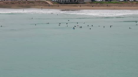 Vista-Aérea-De-Drones-De-Surfistas-En-La-Playa-Y-En-El-Océano-Con-Olas