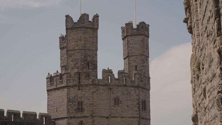 Composizione statica delle torri del castello che si ergono contro un cielo leggermente nuvoloso, inquadratura pulita ed equilibrata. La grandezza del castello da un'angolazione bassa, che ne esalta l'imponente presenza