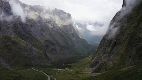 winding road passing thru the mountains, fog, and clouds in milford sound new zealand on the south island